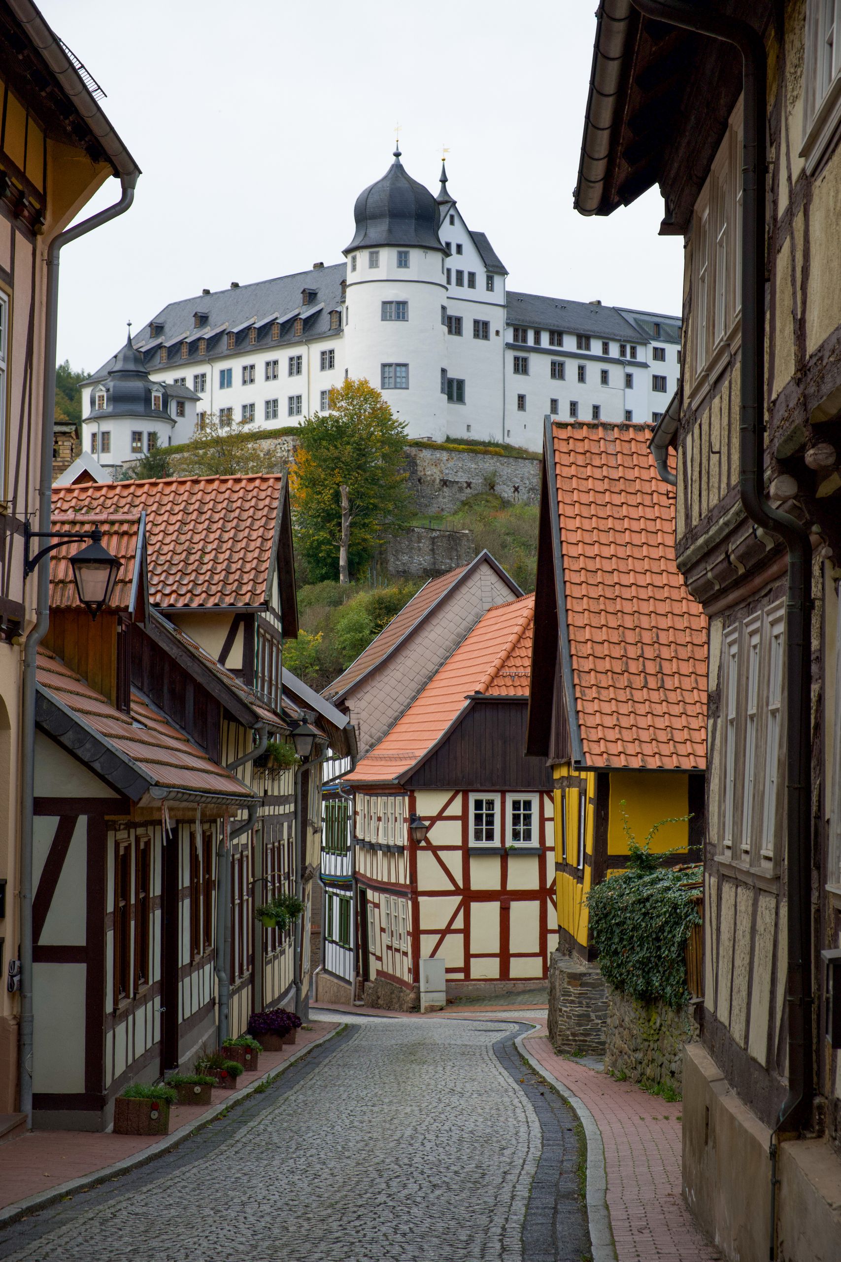 A quaint street in Stolberg, showcasing historic half-timbered houses and a castle.