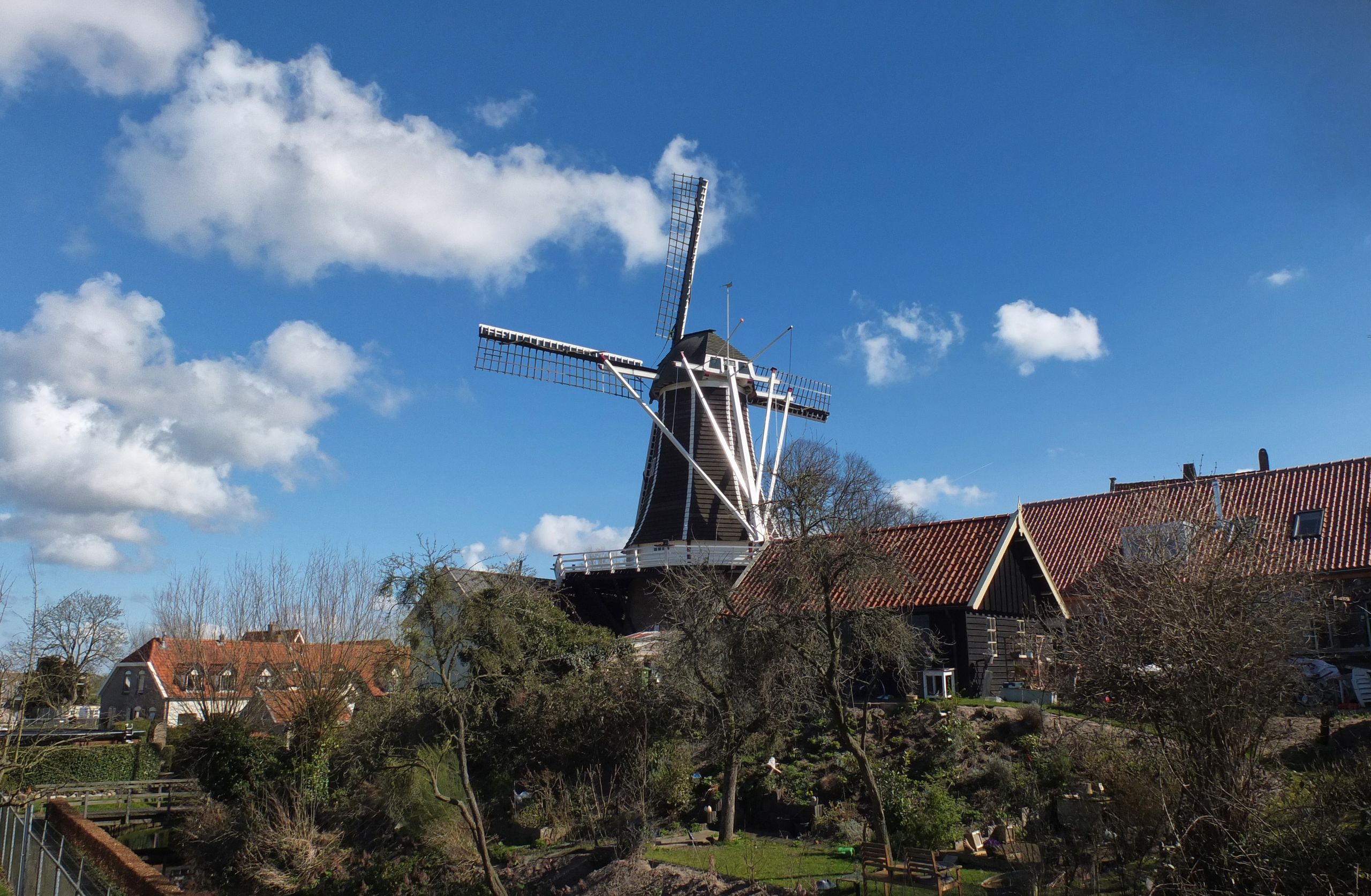 A scenic view of a traditional windmill in Hattem, Gelderland on a sunny day.